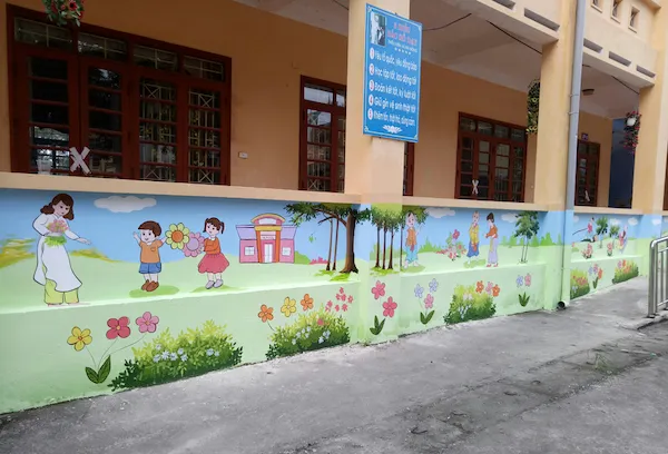 Họa sĩ phác thảo bố cục trước khi tiến hành vẽ tranh tường trường tiểu học