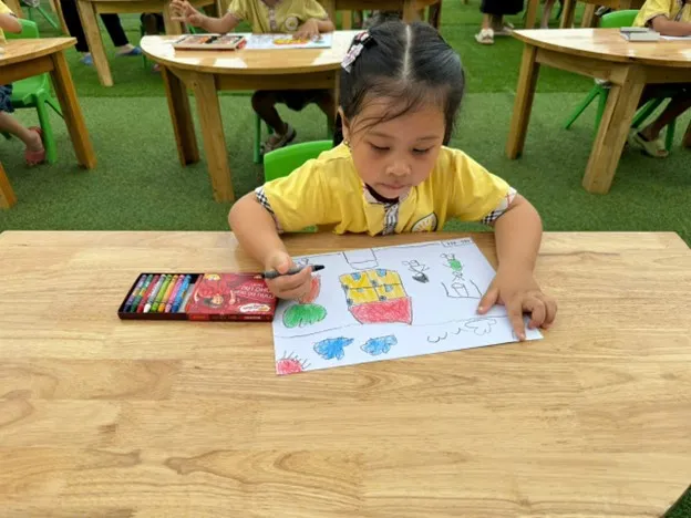 Bé tự hào khoe tác phẩm tranh vẽ chủ đề trường mầm non vừa mới hoàn thành