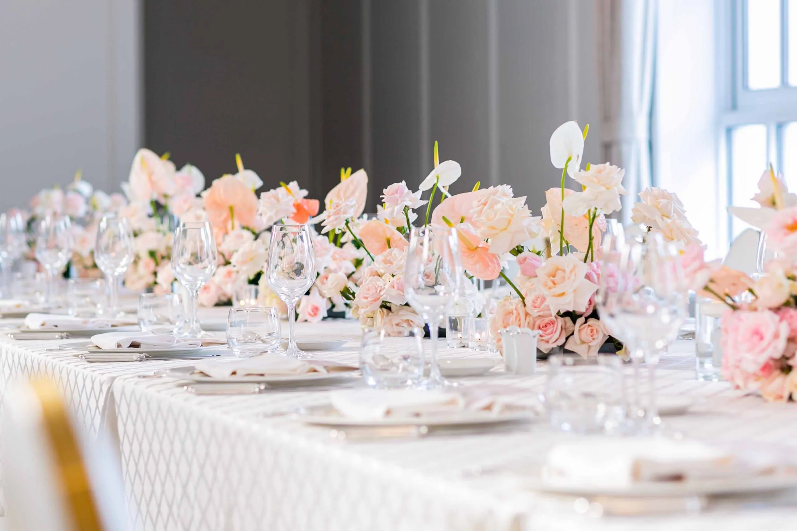 Bàn tiệc kỷ niệm được trang trí lãng mạn với hoa hồng đỏ và khăn trải bàn trắng tinh khôi