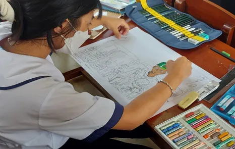 Đôi bàn tay khéo léo của em học sinh đang tỉ mỉ tô màu cho từng chi tiết nhỏ