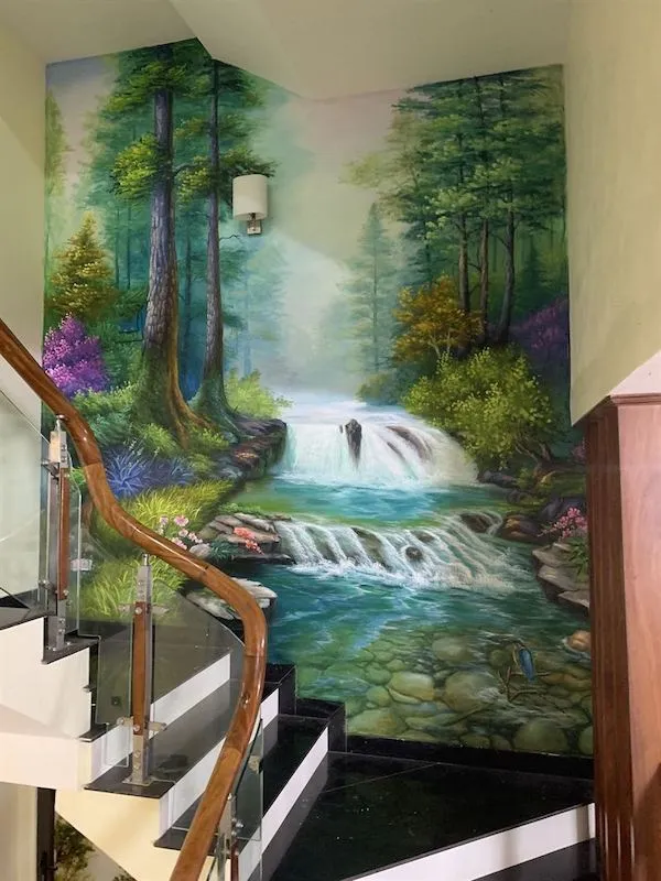 Họa sĩ đang thực hiện vẽ tranh tường phong cảnh thiên nhiên tại lối đi cầu thang