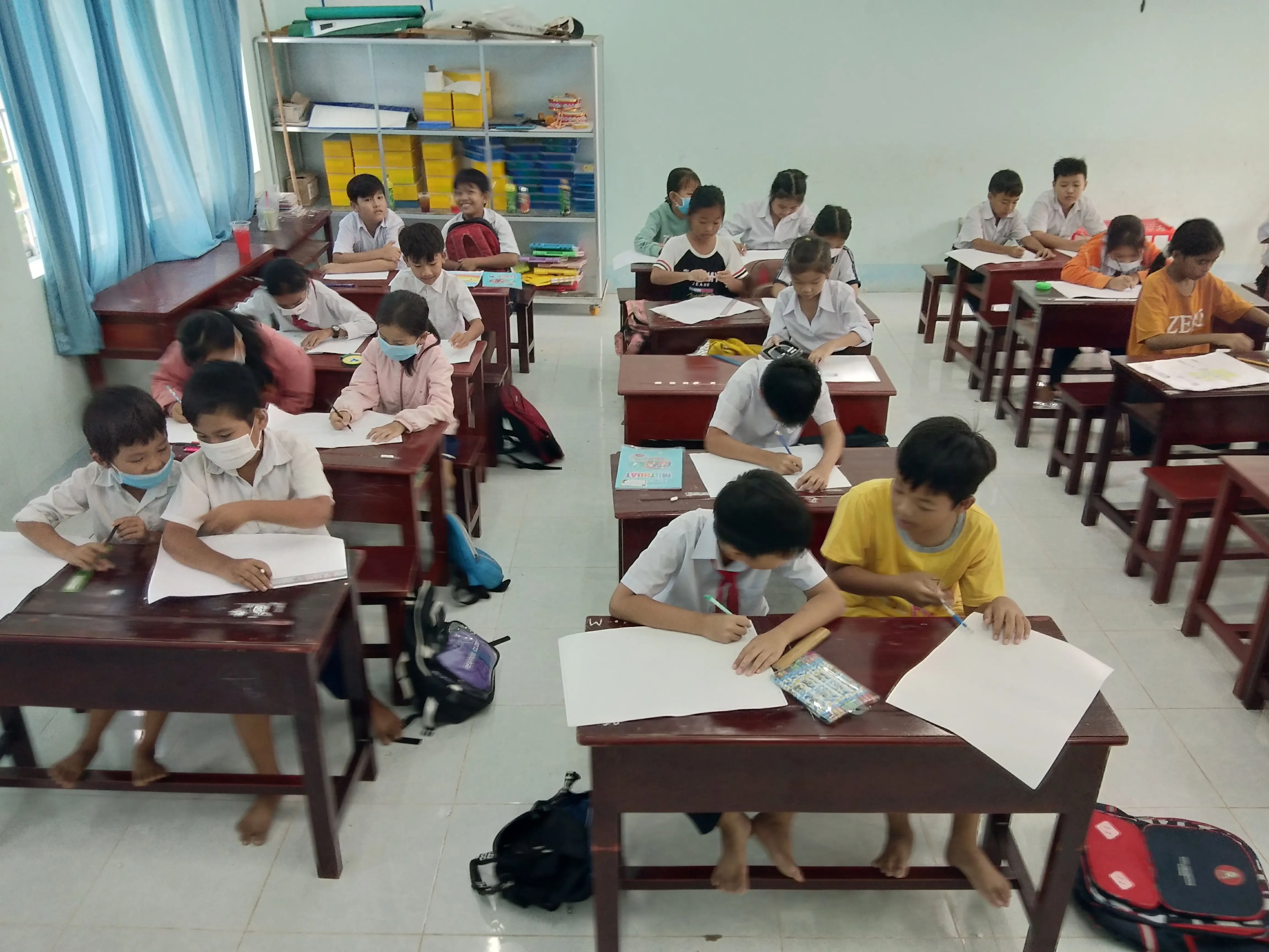 Nhà giáo đang quan sát và hướng dẫn các em cách bố cục màu sắc sao cho hài hòa nhất