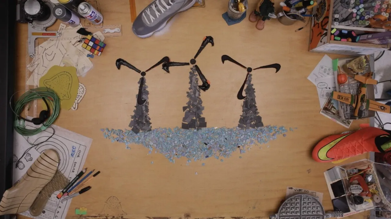 Art piece of wind turbines made from shoe parts on a cluttered wooden tabletop workspace