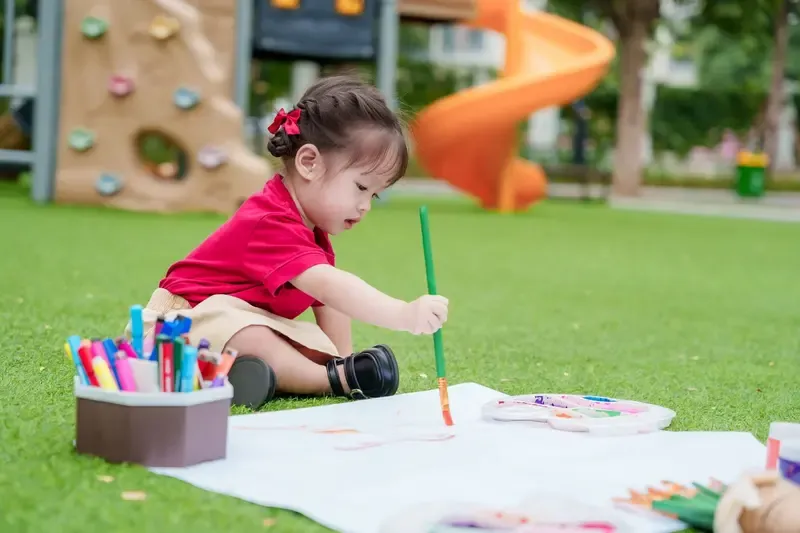 Trẻ nhỏ đang tập trung sử dụng màu sắc để thể hiện ý tưởng độc lập trên giấy